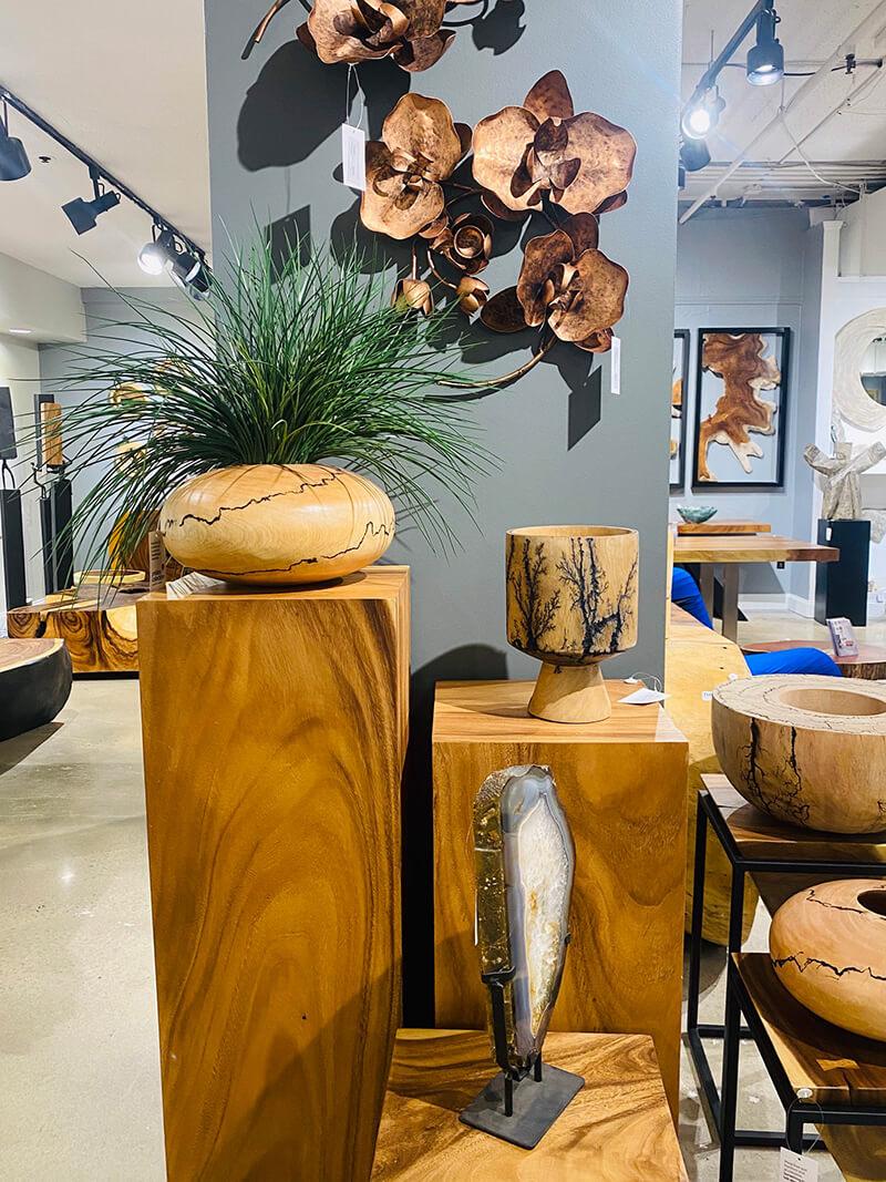 Large wooden block accent tables at three different heights with wood carved pots and vases